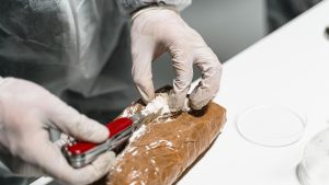 Photo of man in gloves opening cocaine package