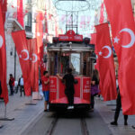 Image of a line of Turkey Flags with kids riding on the back of a tram in Istanbul