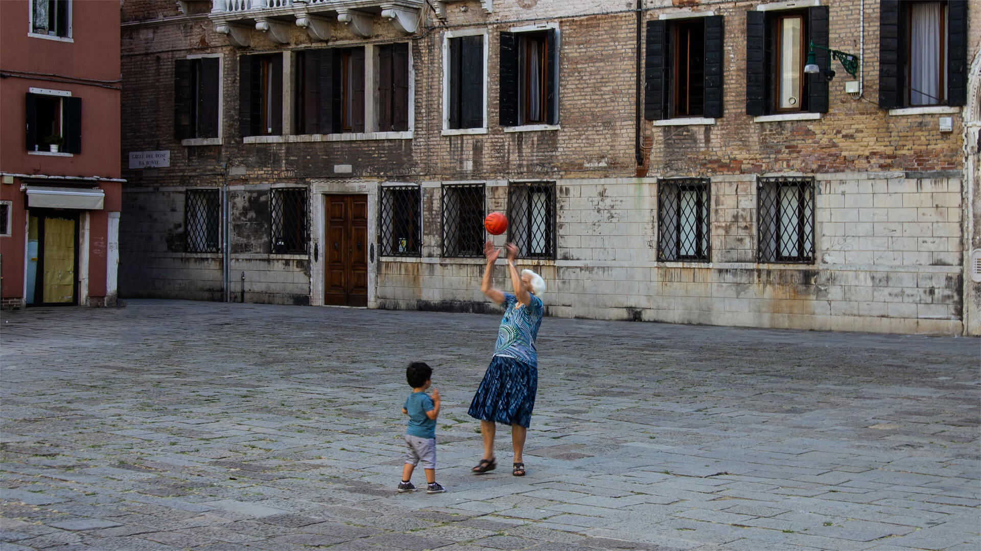 An elder woman plays basketball with a child