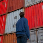 Photo of man standing in front of trade shipping containers