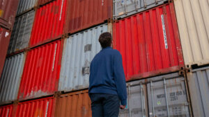 Photo of man standing in front of trade shipping containers