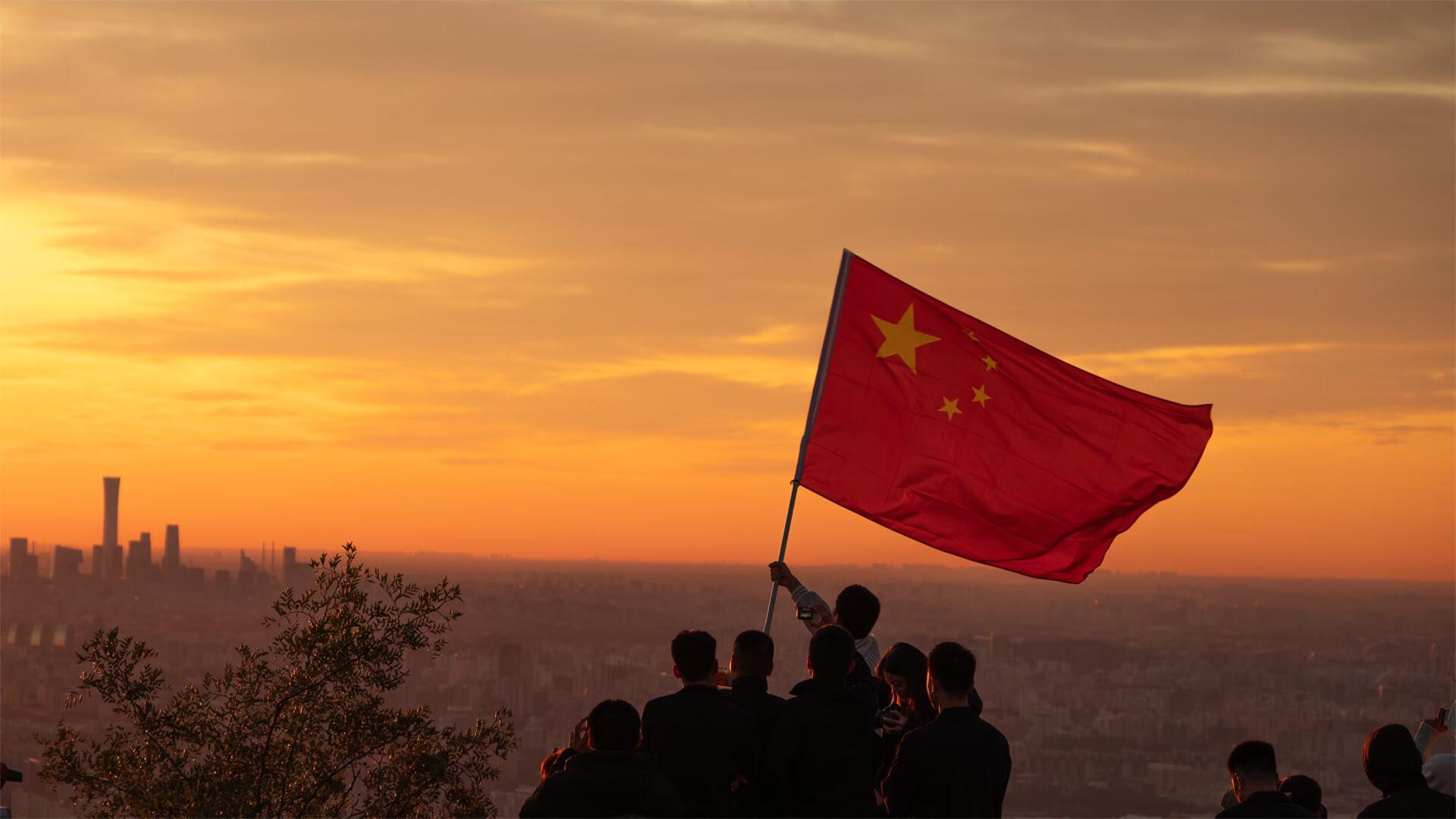 A group of people on a hill hoisting up a Chinese flag