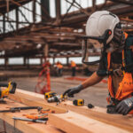 A construction workers cuts lumber in a mask