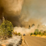 Wildfires with smoke and a car in the background