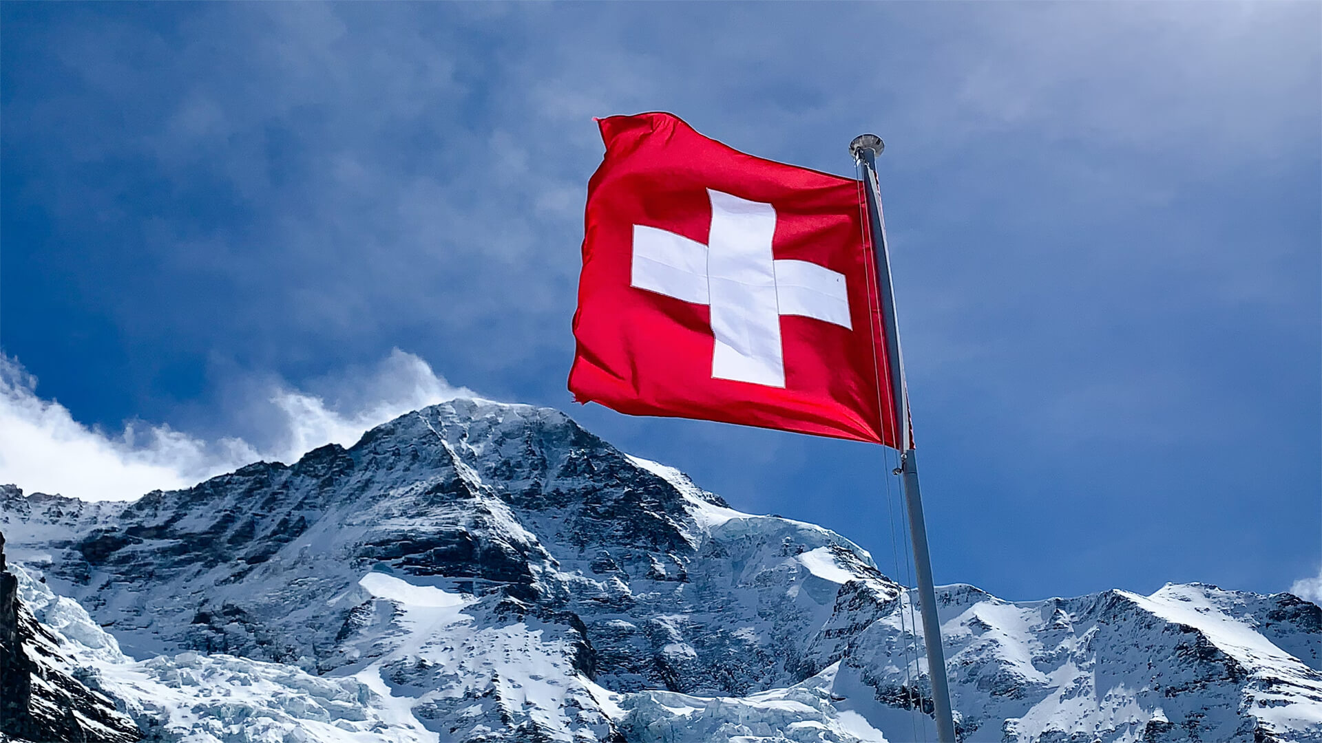 Swiss flag over snow capped mpuntains
