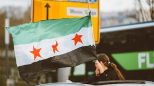 Woman holding a Syrian flag over a vehicle