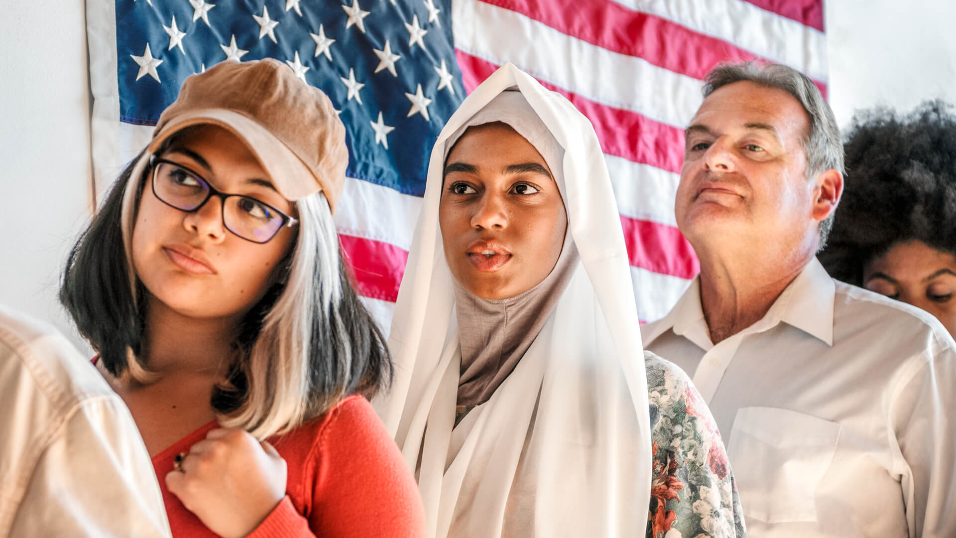 Immigrants standing in line in front of an American flag | Licensed by Envato Elements