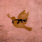 Mural on a wall with a dove with an AK-47 inside