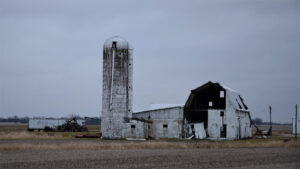 Large white barn in imploding stage with white concrete silo