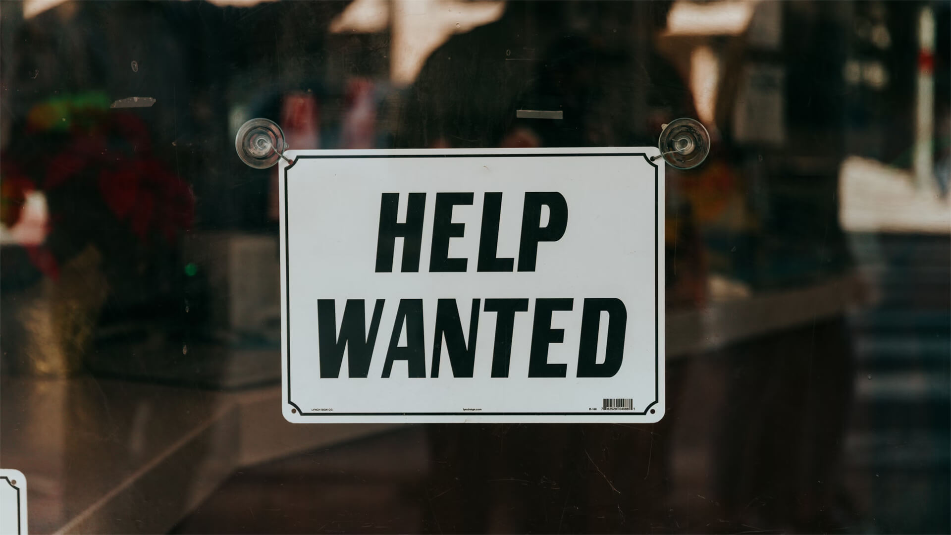 Sign reading "Help Wanted" in a window