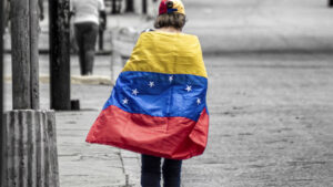 A person walking draped in a Venezuelan flag against a desaturated background
