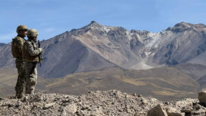 Two Chilean soldiers standing in front of a mountain