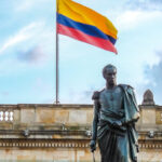 the statue of Simón Bolívar standing before Colombia’s National Capitol, with the flag waving