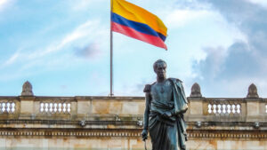 the statue of Simón Bolívar standing before Colombia’s National Capitol, with the flag waving