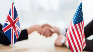 US and UK flags with a selective focus on diplomats shaking hands. Licensed by Envato Elements