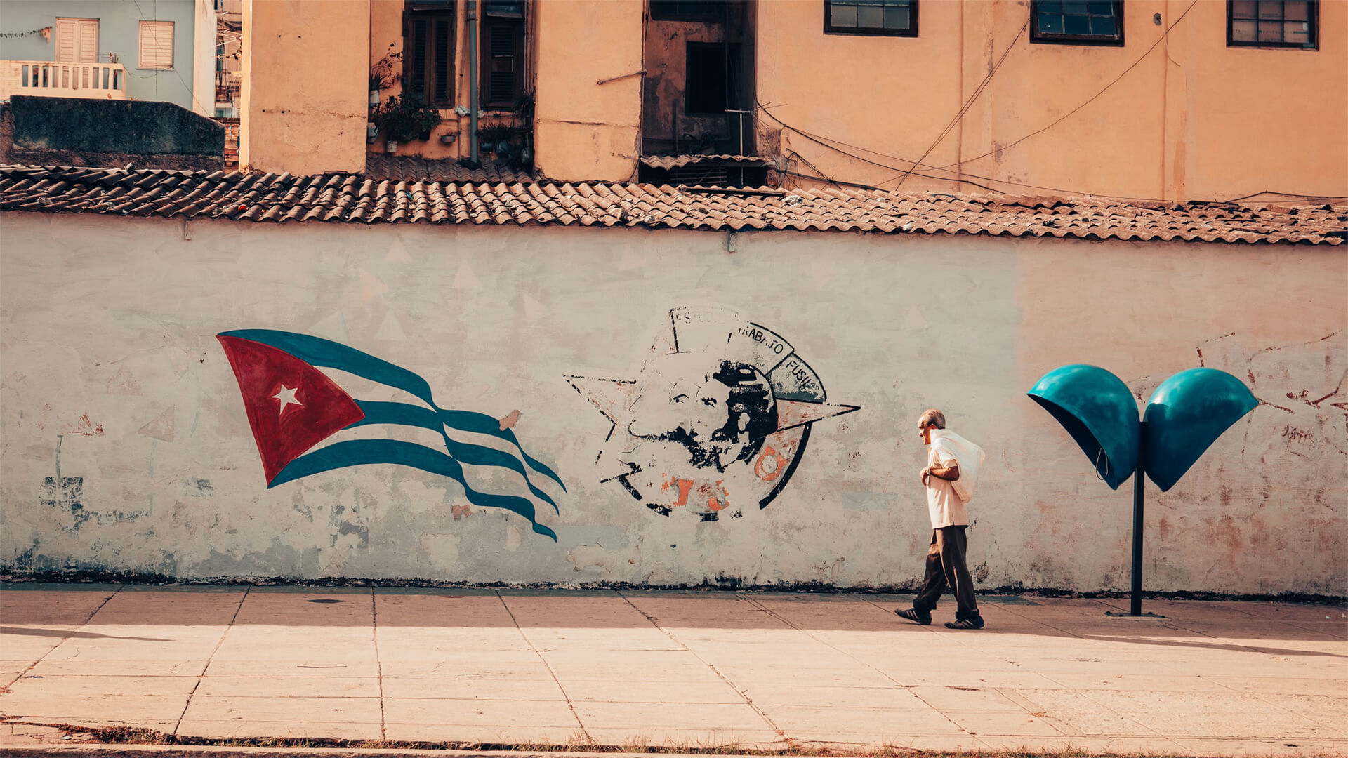 Man walking in front of Cuban mural