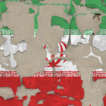 A ripped grungy back wall of the Iranian flag