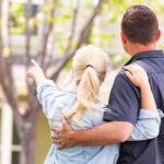 A Caucasian couple staring and pointing at a home