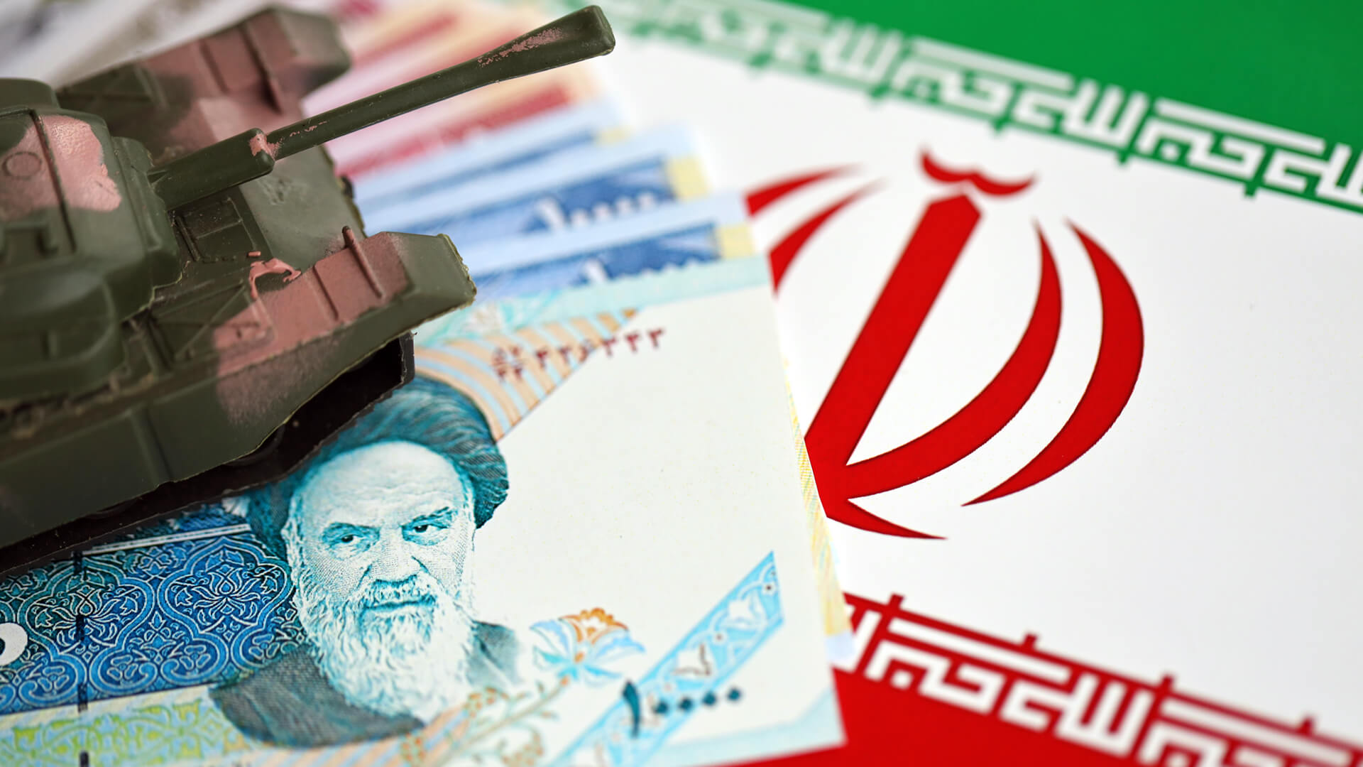 Toy Tank Atop Iranian Currency and Flag | Licensed by Envato Elements: https://app.envato.com/search/photos/3abc94ac-73db-4912-ae0d-3e507dd11191?itemType=photos&term=iran+war