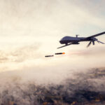 Drone Aircraft Dropping Bombs over Misty Landscape | Photo licensed by Envato Elements: https://app.envato.com/search/photos/c058515b-6f36-40c6-837a-4f0644a0809e?itemType=photos&term=military+drone