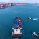 Shipping containers being transported by a cargo hauler in a strait | Licensed by Envato Elements