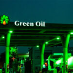 A green lit gas station with an oil tanker