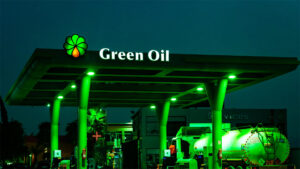 A green lit gas station with an oil tanker
