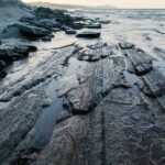 Coastal shoreline with shale looking rocks in water | Photo by Envato Elements