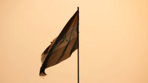 Flag of Iraq, torn and tattered against a desert sun